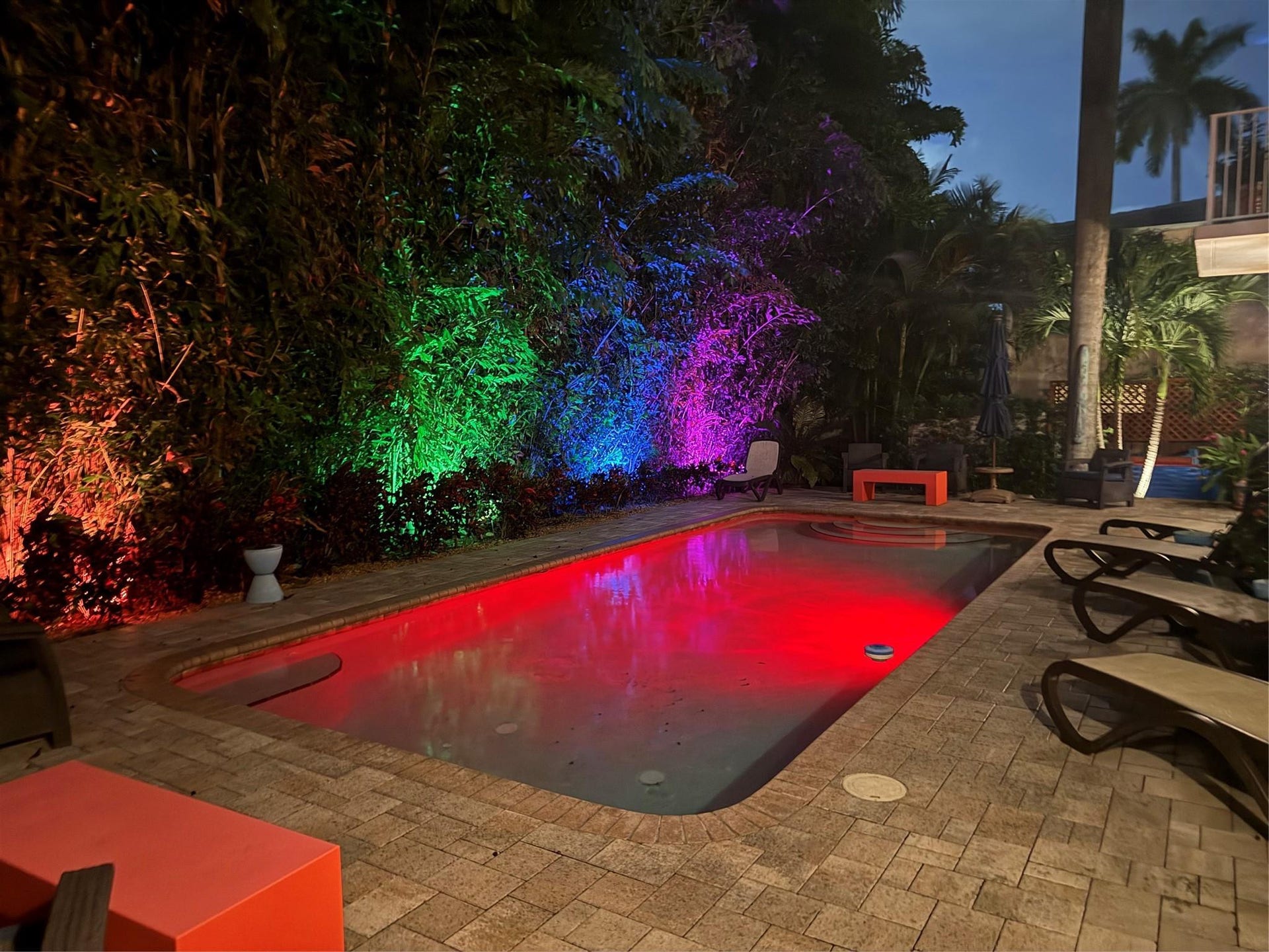 Pool illuminated at night with color-changing lights.