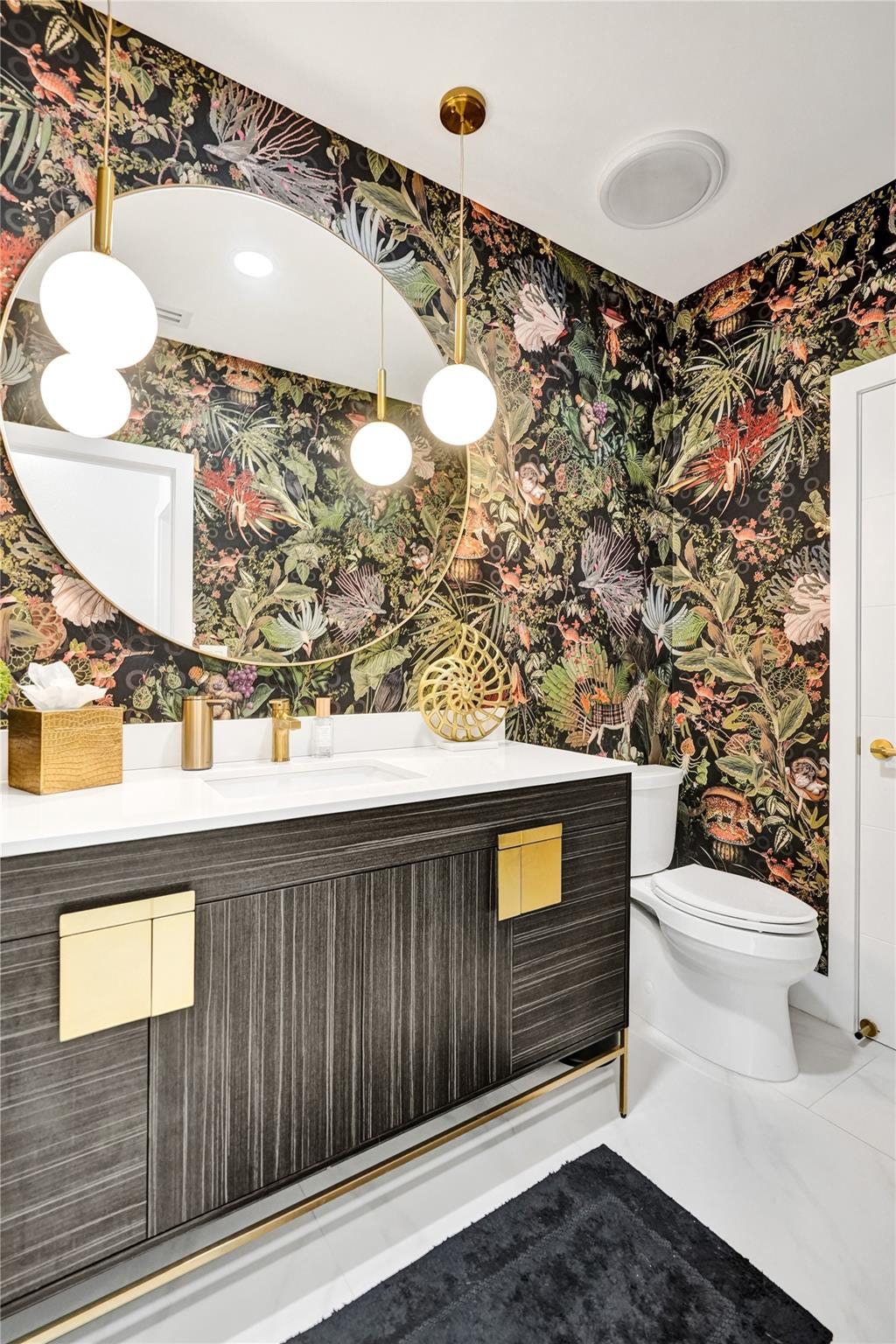 Designer powder bath with wallpaper and gold accents.