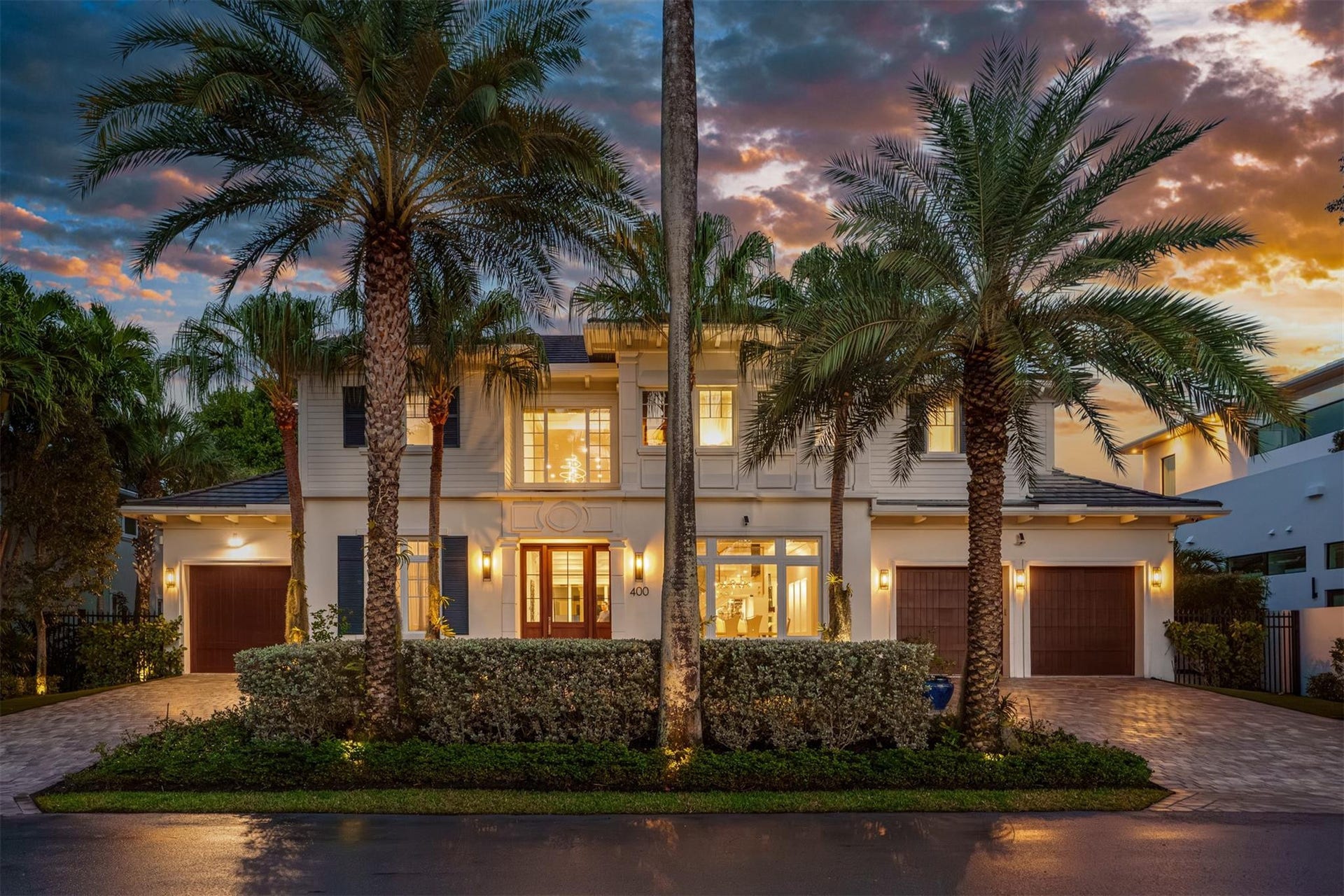 Front-facade of the home beautifully illuminated at night with 3 car garage and additional space for parking and guests.