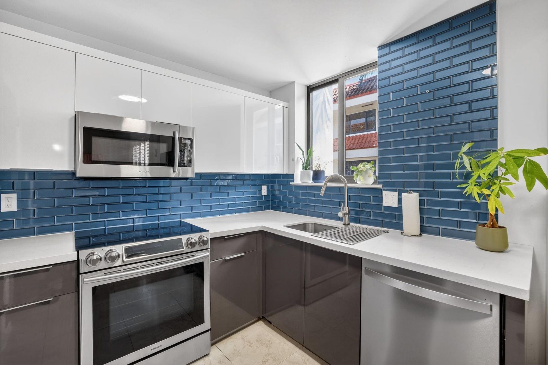 1401 NE 9th Street, #13, Fort Lauderdale, FL 33304 The kitchen also features modern 2-tone cabinetry, stainless steel appliances, and a striking blue tile backsplash.