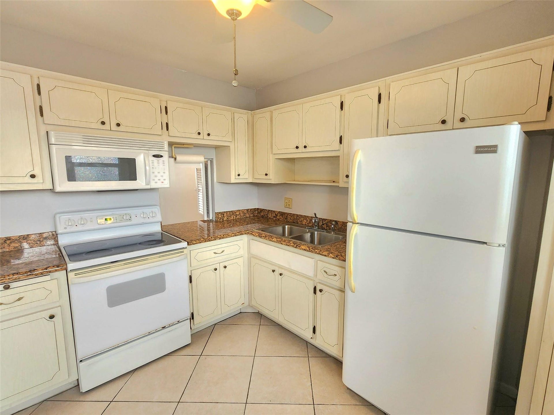 2223 Park Lane, #105, Hollywood, FL 33021 The kitchen is at the front of the property with neutral cabinets, a large window for plenty of natural light, granite counters, and a pass through to the dining area.