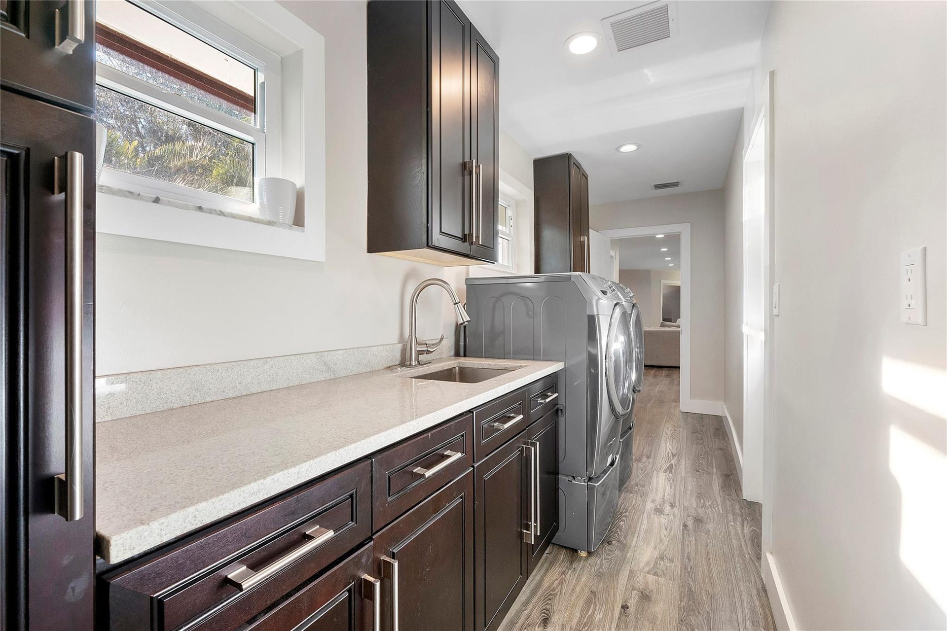 5351 Godfrey Road, Parkland, FL 33067 The laundry room in the big house has lots of folding & storage space and its own sink, matching cabinets to the kitchen in walnut with chrome hardware,
