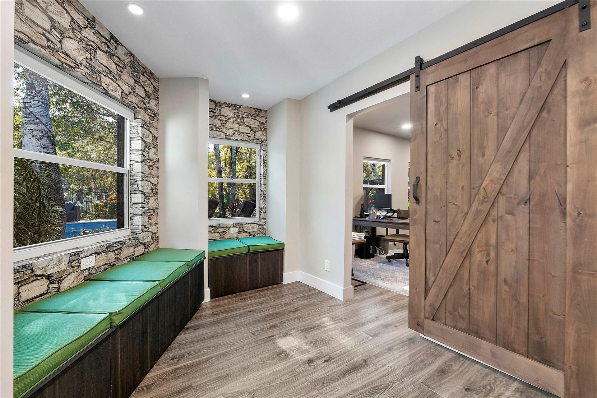 5351 Godfrey Road, Parkland, FL 33067 The quiet reading room with stone accent walls and a wide open barn door that leads into an office or den for complete privacy at the back of the house with the windows looking out onto the serene pool and garden.