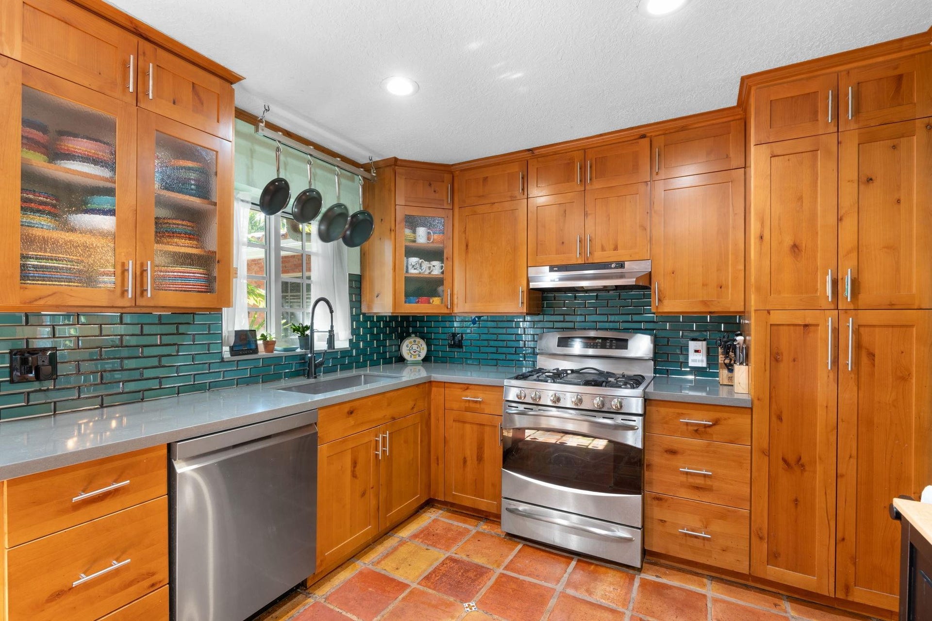 2956 NW 6th Terrace, Wilton Manors, FL 33311 U-shaped kitchen layout with extensive cabinetry, quartz counters, and under-cabinet lighting. Glass door offers convenient access to the outdoor area and enhances the light-filled workspace.