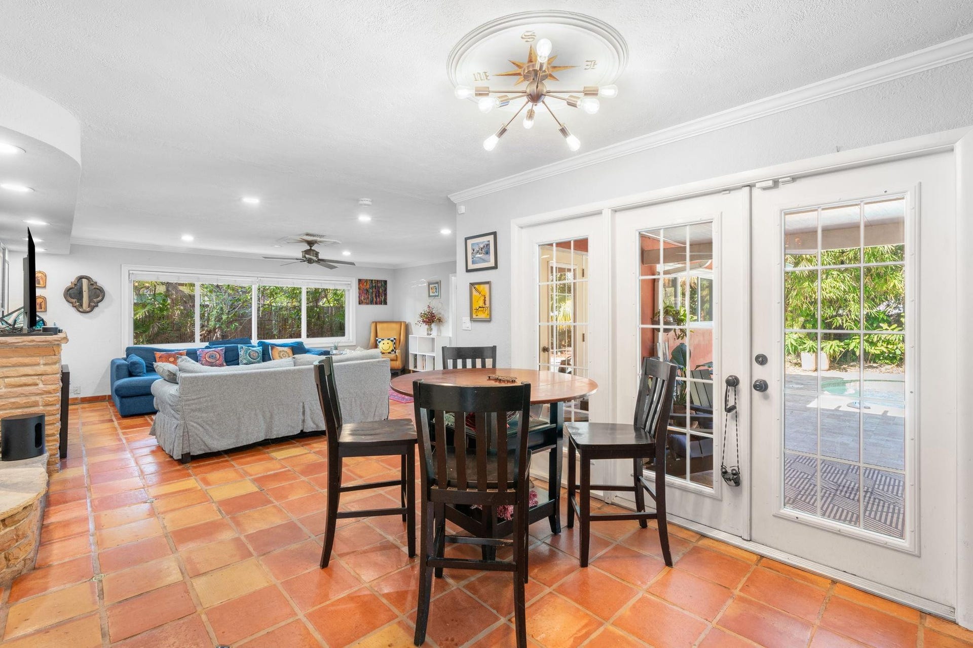 2956 NW 6th Terrace, Wilton Manors, FL 33311 Dining space with terracotta tile floors and French doors providing access to the outdoor patio. Statement light fixture and adjacent open living area create an easy flow for gatherings.
