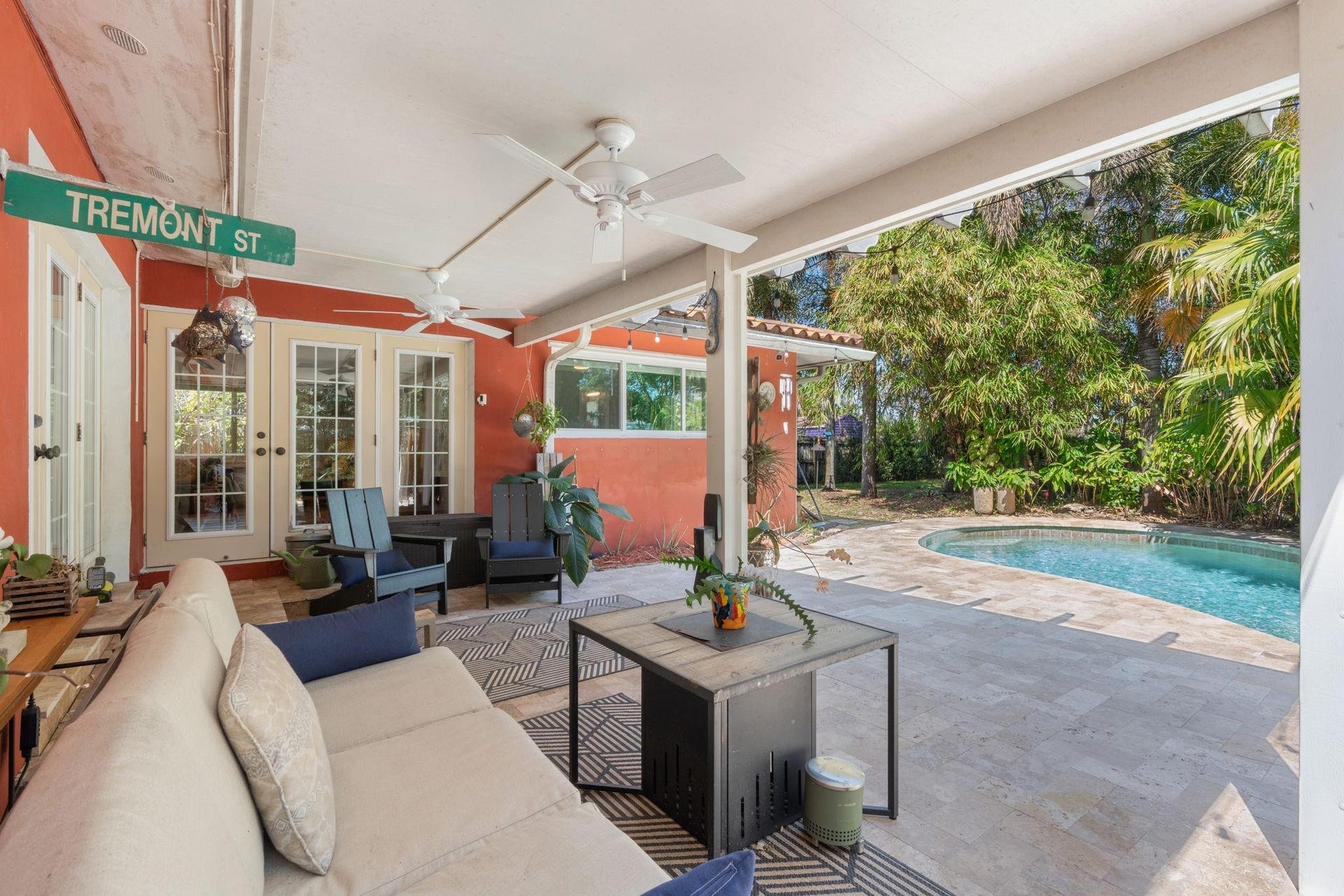 2956 NW 6th Terrace, Wilton Manors, FL 33311 Outdoor living area with French door entry, tiled steps, and ample shaded space for seating and dining. Ceiling fans enhance year-round comfort.