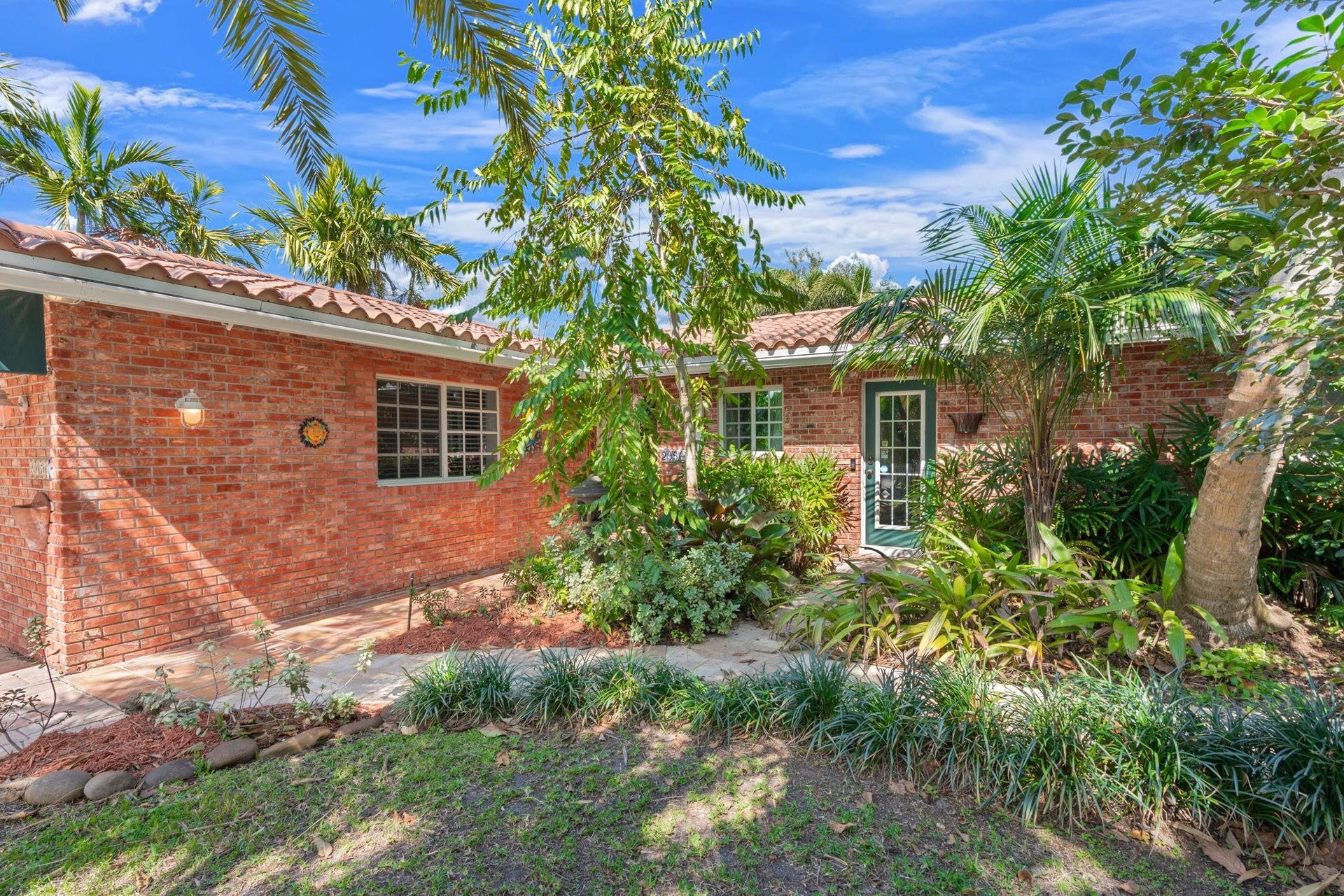 2956 NW 6th Terrace, Wilton Manors, FL 33311 Inviting front entry with brick faade, tiled walkway, and decorative greenery. Covered approach provides shade and a welcoming first impression.