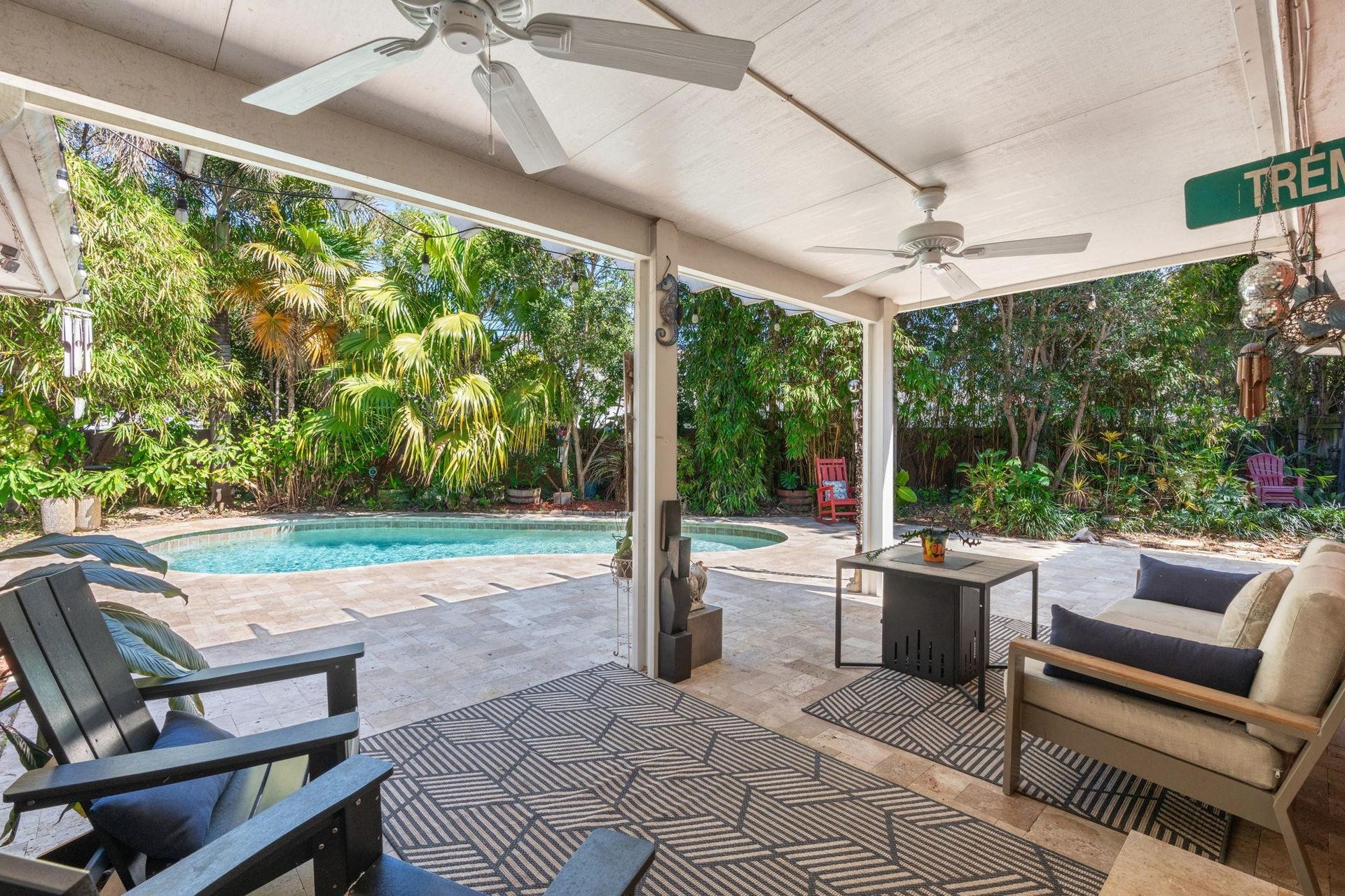 2956 NW 6th Terrace, Wilton Manors, FL 33311 Covered patio with ceiling fans, recessed lighting, and travertine-style paver flooring. Spacious layout offers comfortable seating and seamless access to the pool area.