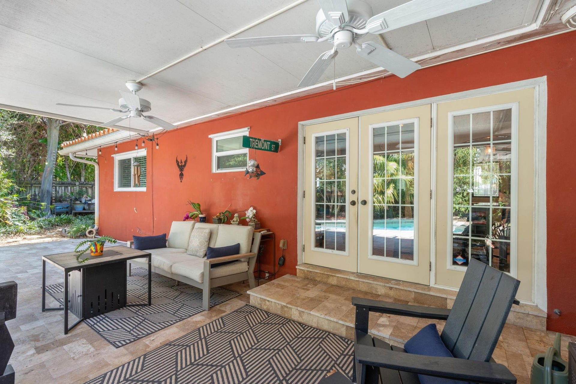 2956 NW 6th Terrace, Wilton Manors, FL 33311 Covered patio featuring French doors, ceiling fans, and tiled flooring. Shaded seating area overlooks the pool and landscaped yard.