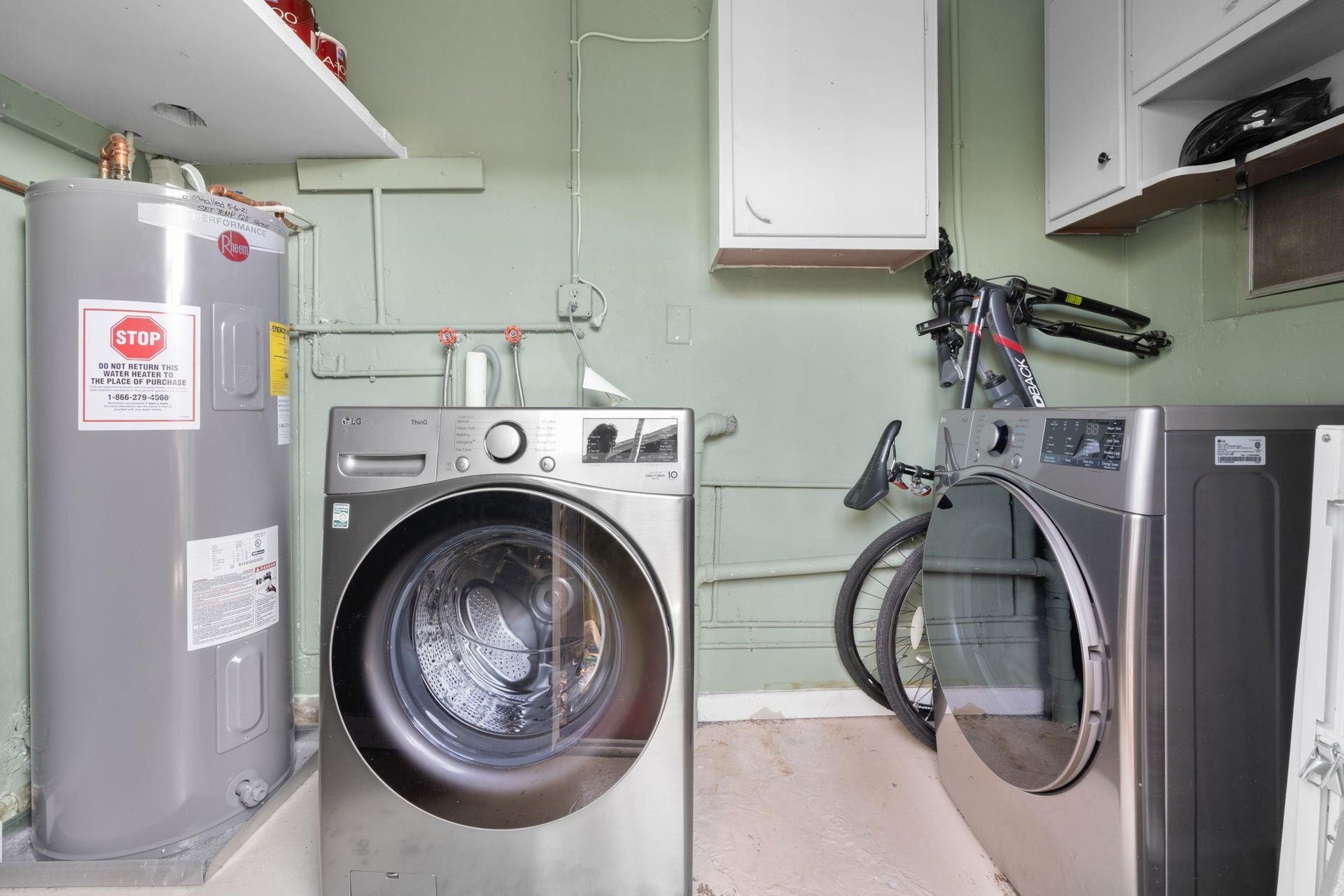 2956 NW 6th Terrace, Wilton Manors, FL 33311 Laundry area with front-load washer and dryer, and wall-mounted storage cabinets. Dedicated space offers convenient household functionality.