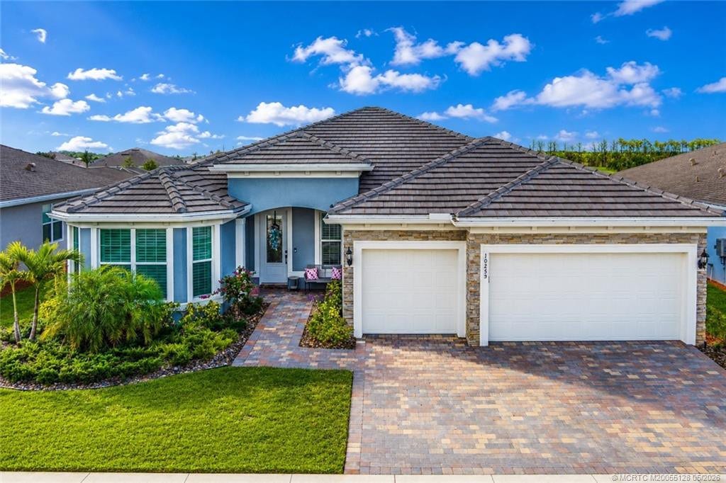Stunning exterior view of this beautifully designed 3-bedroom, 3-bath residence in Del Webb at Tradition. Featuring elegant stone accents, a paver driveway, lush tropical landscaping, and a spacious 3-car garage, this home offers outstanding curb appeal in one of Traditions premier active adult communities. Thoughtfully designed with quality finishes and located close to resort-style amenities, shopping, dining, medical facilities, and major highways.