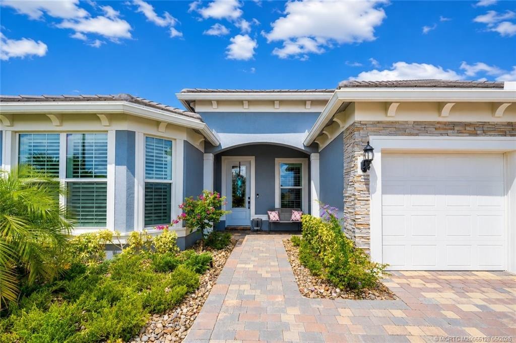 Inviting covered entry welcomes you to this beautifully maintained 3-bedroom, 3-bath home in Del Webb at Tradition. Enjoy impressive curb appeal with upgraded stone accents, elegant paver walkway and driveway, manicured tropical landscaping, and a charming front sitting area perfect for relaxing and greeting guests. Thoughtfully designed with quality finishes and located in one of Traditions premier active adult communities.