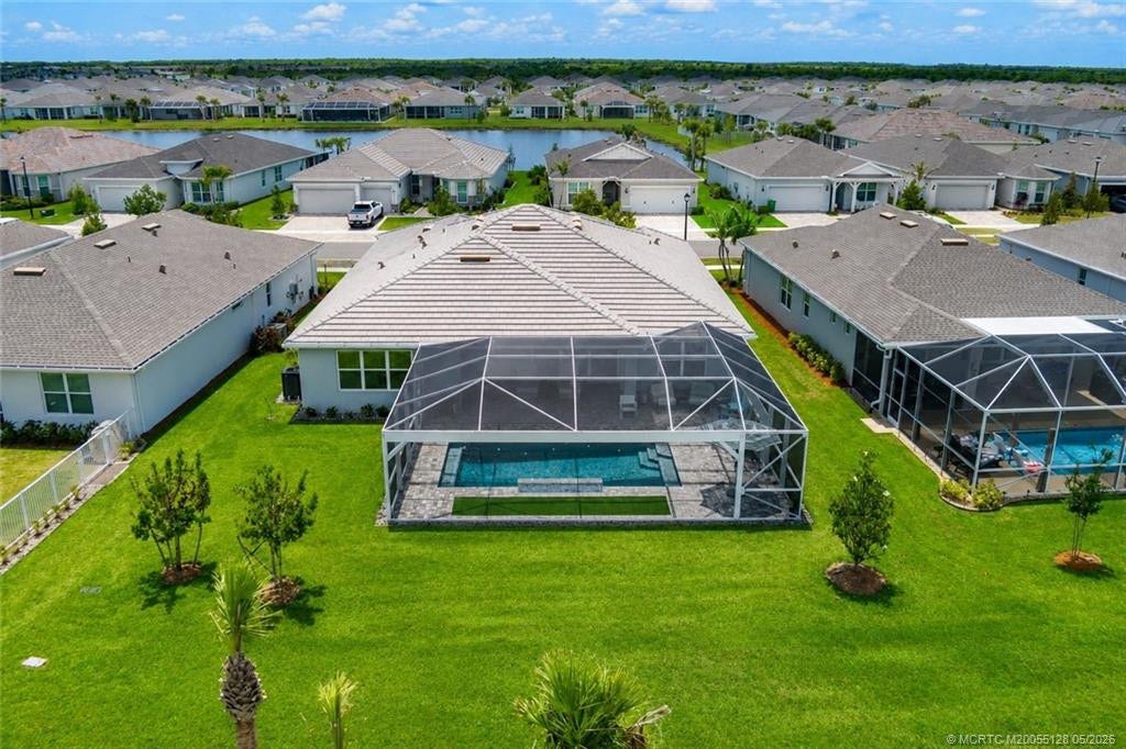 Aerial rear view highlights the homes expansive screened pool enclosure, oversized lanai, and generous backyard with peaceful preserve views and no rear neighbors immediately behind. This premium lot offers exceptional privacy and plenty of outdoor space to enjoy the Florida lifestyle in Del Webb at Tradition.