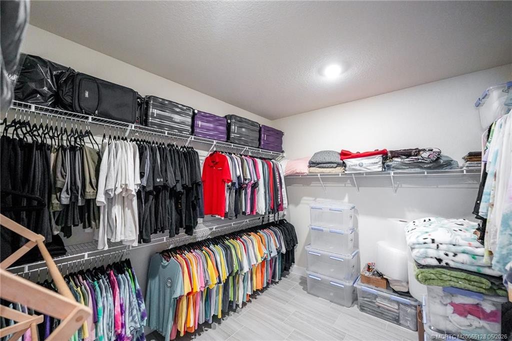 Spacious walk-in primary closet offers abundant storage with extensive shelving and hanging space, providing excellent organization for clothing, shoes, and accessories. Thoughtfully designed for convenience and functionality, this oversized closet complements the homes luxurious primary suite.
