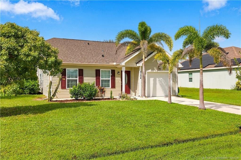 2134 SE Gaslight Street, Port St Lucie, FL 34952 Single-story home with light exterior, covered entry, and mature landscaping