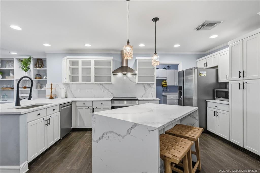 2657 SW Harem Circle, Port St Lucie, FL 34953 Beautifully appointed kitchen featuring crisp white cabinetry, generous counterspace, stainless steel appliances, and an island