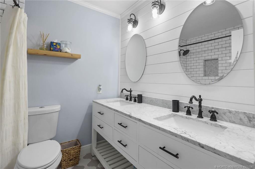 2657 SW Harem Circle, Port St Lucie, FL 34953 Guest bathroom with double sinks, countertops, black fixtures, and coastal-inspired shiplap accents