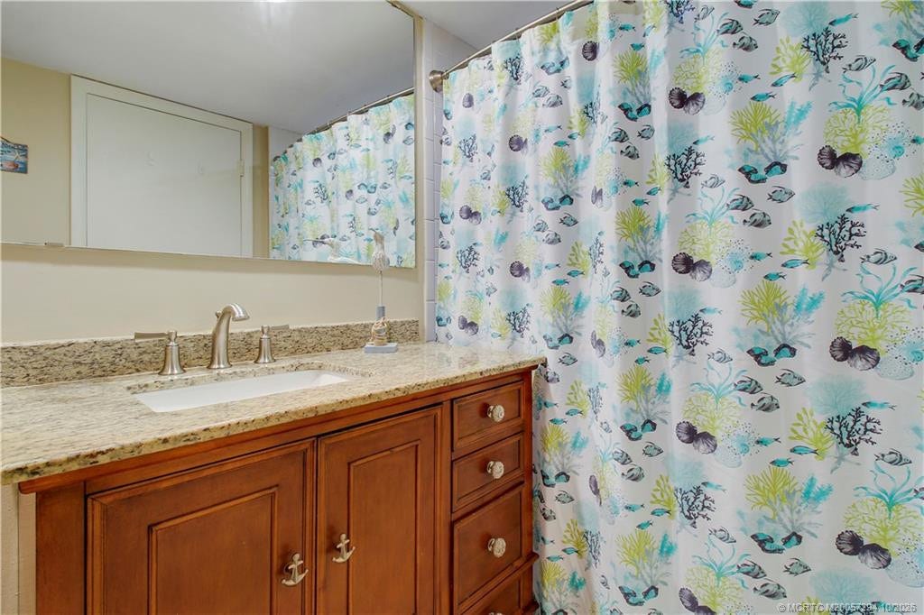 Another view of the guest bathroom highlights the generous granite countertop, ample vanity storage, and tub/shower combination, offering comfort and convenience for visiting family and friends.