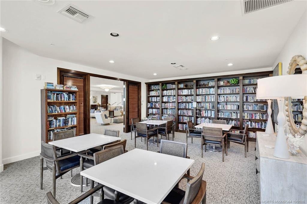 Spacious community library featuring an extensive collection of books, comfortable seating, and tables for cards and games.