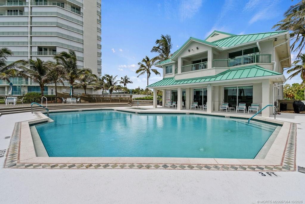 Beautiful resort-style pool area featuring a convenient poolside building with indoor facilities, restrooms, and an outdoor shower.