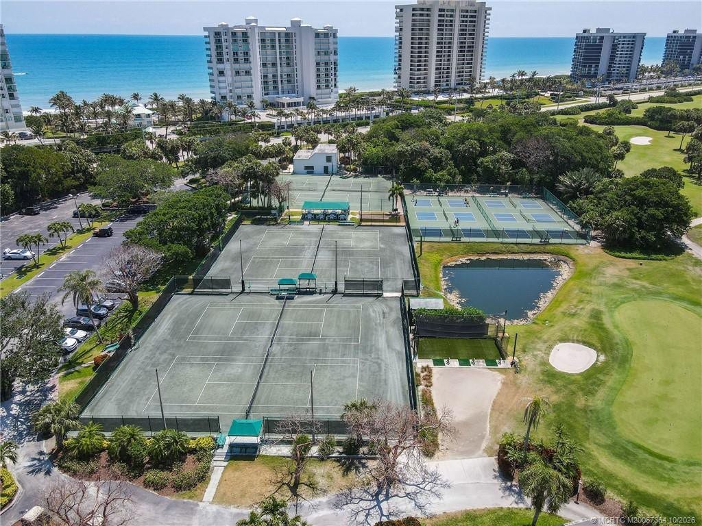 Aerial view highlighting the extensive tennis and pickleball facilities, golf course, and riverside clubhouse and marina.