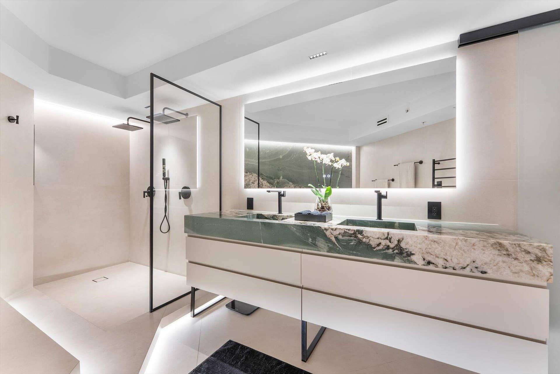Primary Bathroom of elevated design with Intermare quartzite surfaces, 48x48 imported Spanish tile, and a custom-crafted tub wall that exudes
modern European luxury.