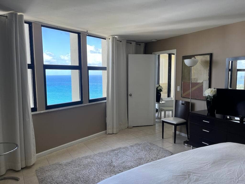 Expansive window wall with ocean backdrop, tiled flooring, and neutral wall tones