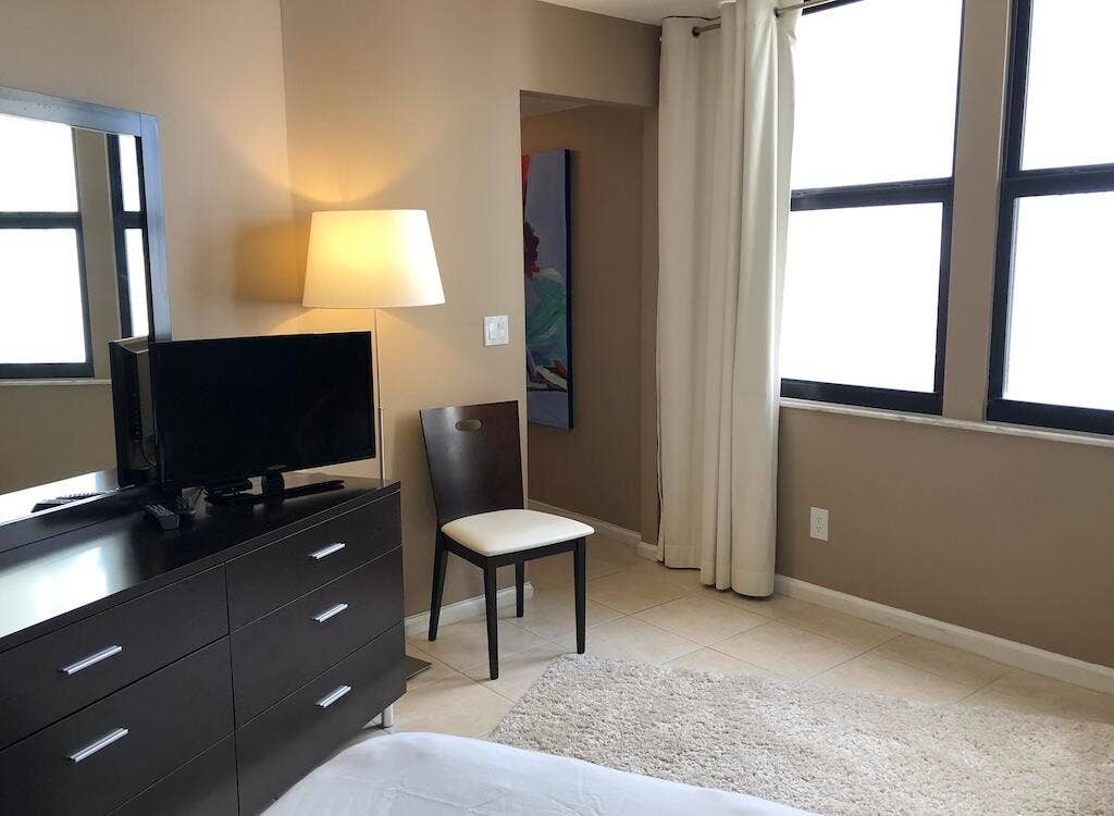 Wall-mounted mirror, multiple large windows, natural tone wall paint, tile flooring, and a built-in wall niche