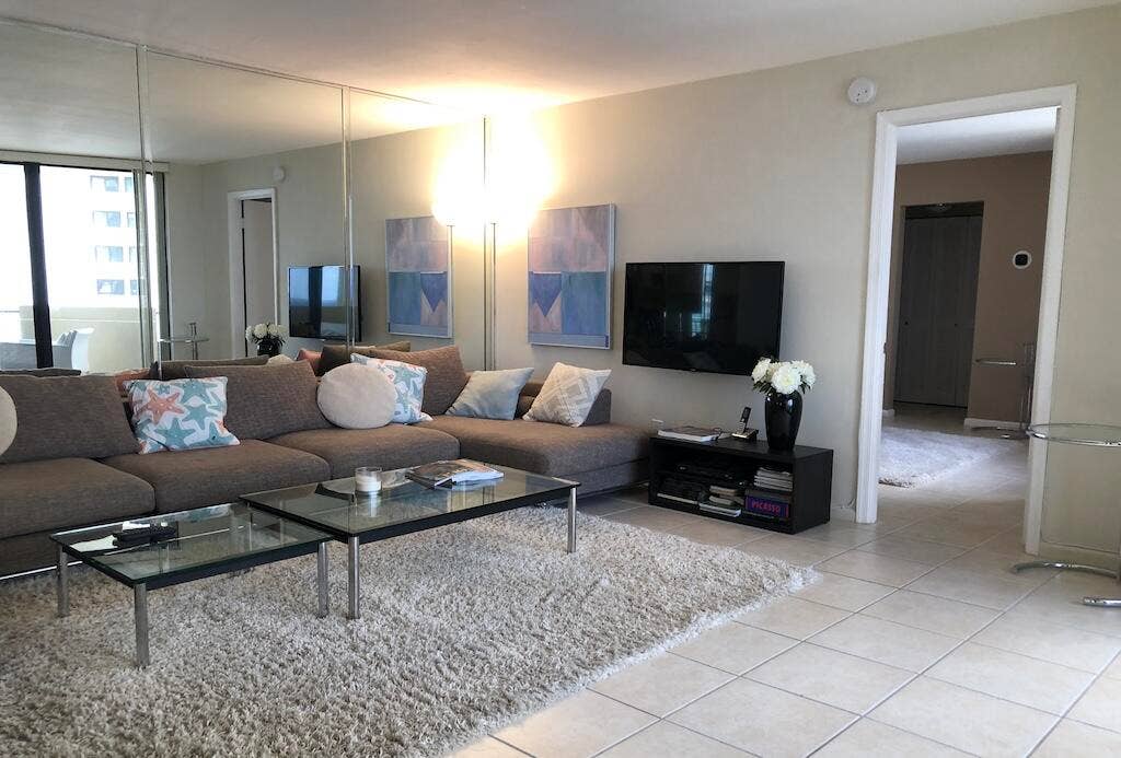 Mirrored wall accent, tile flooring, and a wall-mounted television