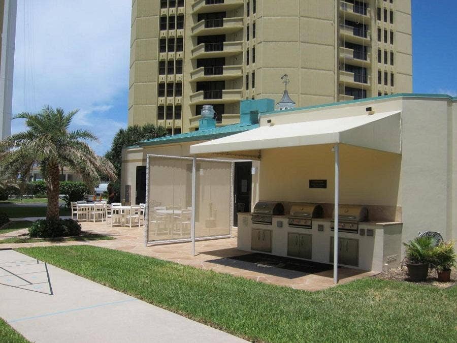 Outdoor kitchen featuring three built-in grills, stone-finish countertops, and under-counter storage
