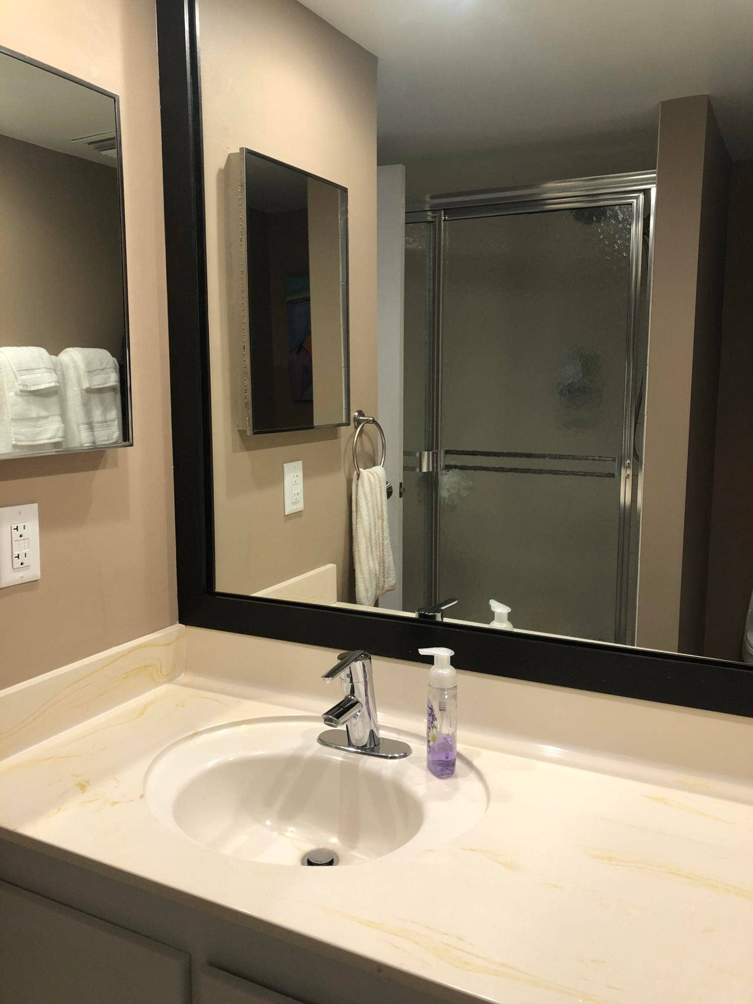 Bathroom vanity with an integrated sink, polished chrome faucet, and a large framed wall mirror