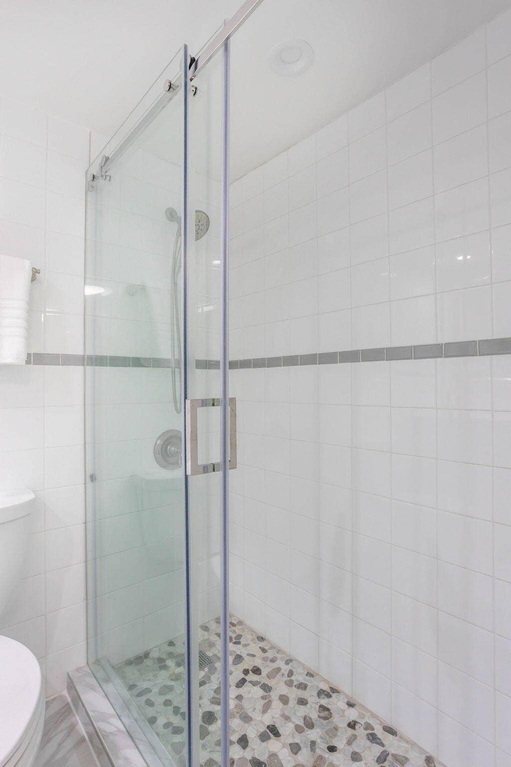 Glass enclosed shower with sliding door and custom tile details