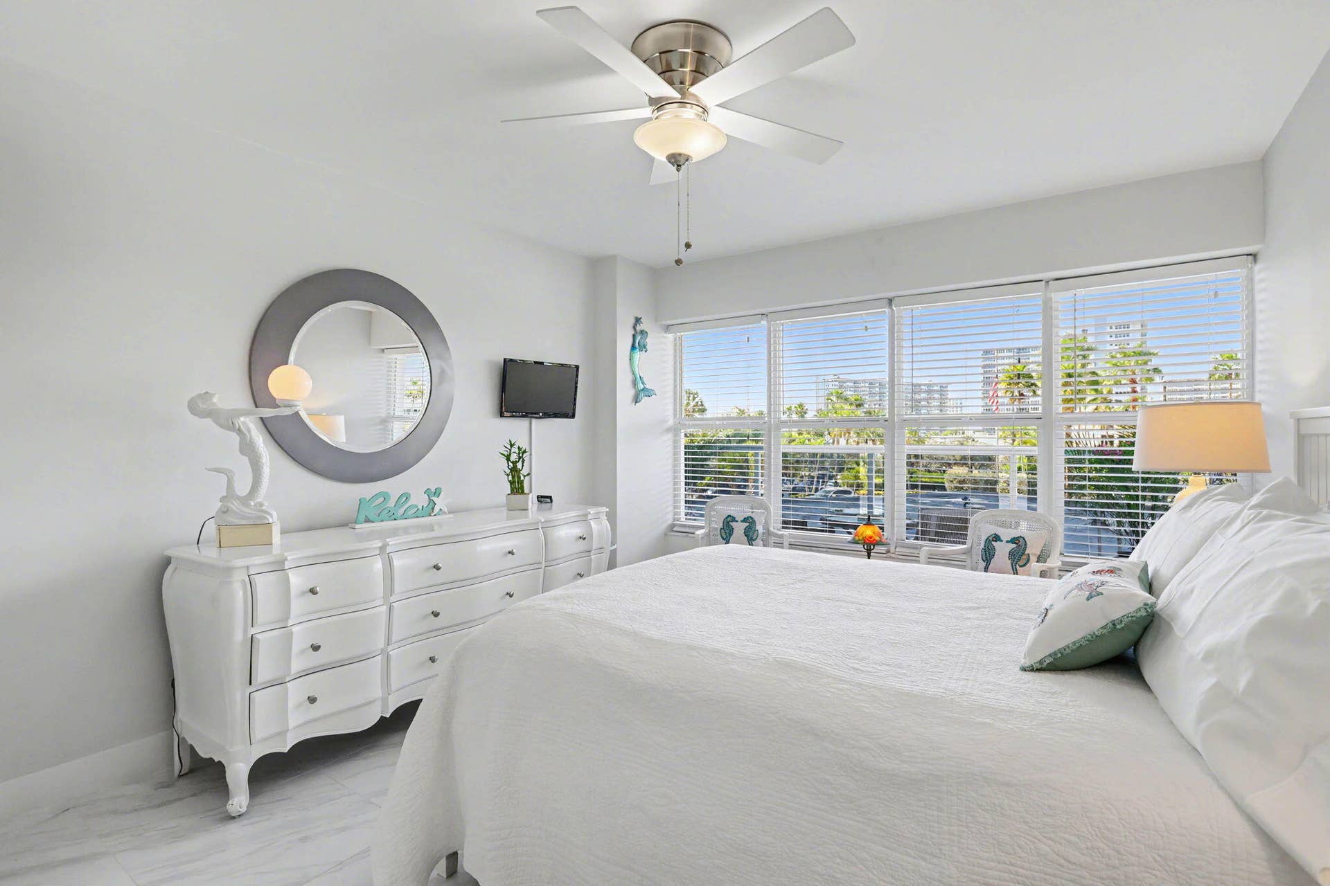 Spacious bedroom including ceiling fan, window blinds and neutral ceramic tile floors