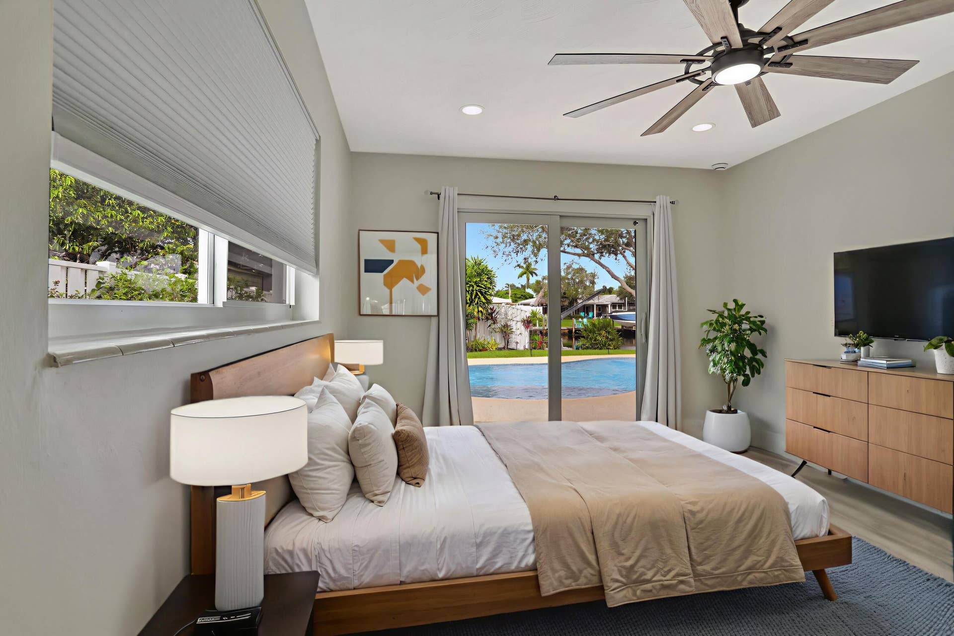 421 SE 5 Terrace, Pompano Beach, FL 33060 Bedroom facing the pool/ water can be Primary Suite or Bedroom #2. Both bedrooms are on suites. Storm sliders lead to the pool/deck. This photo is virtually staged.