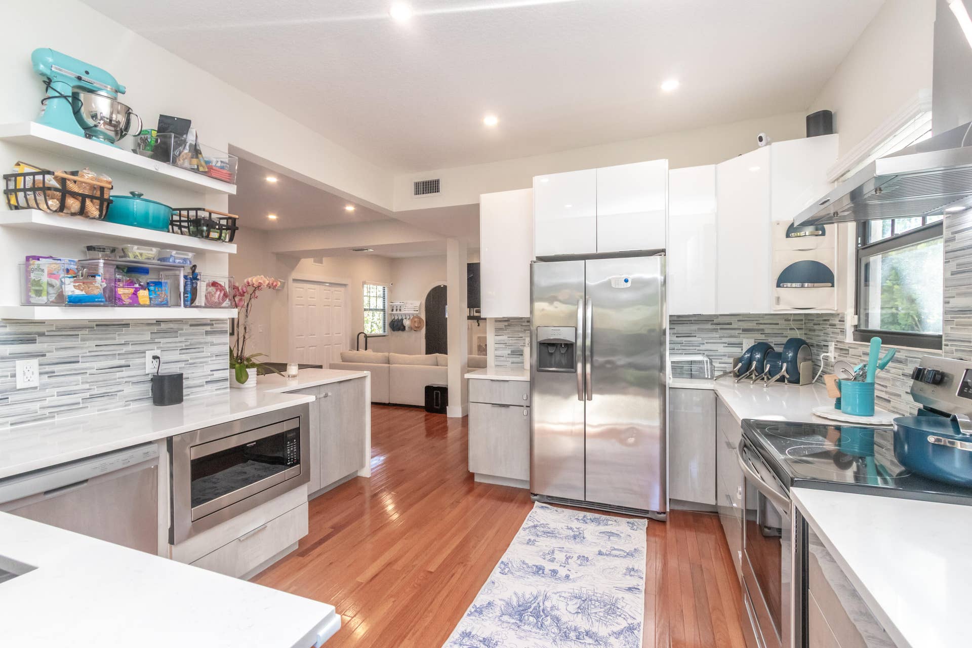Large kitchen with quartz countertops, glass backsplash, under-counter microwave, & stainless steel-appliances