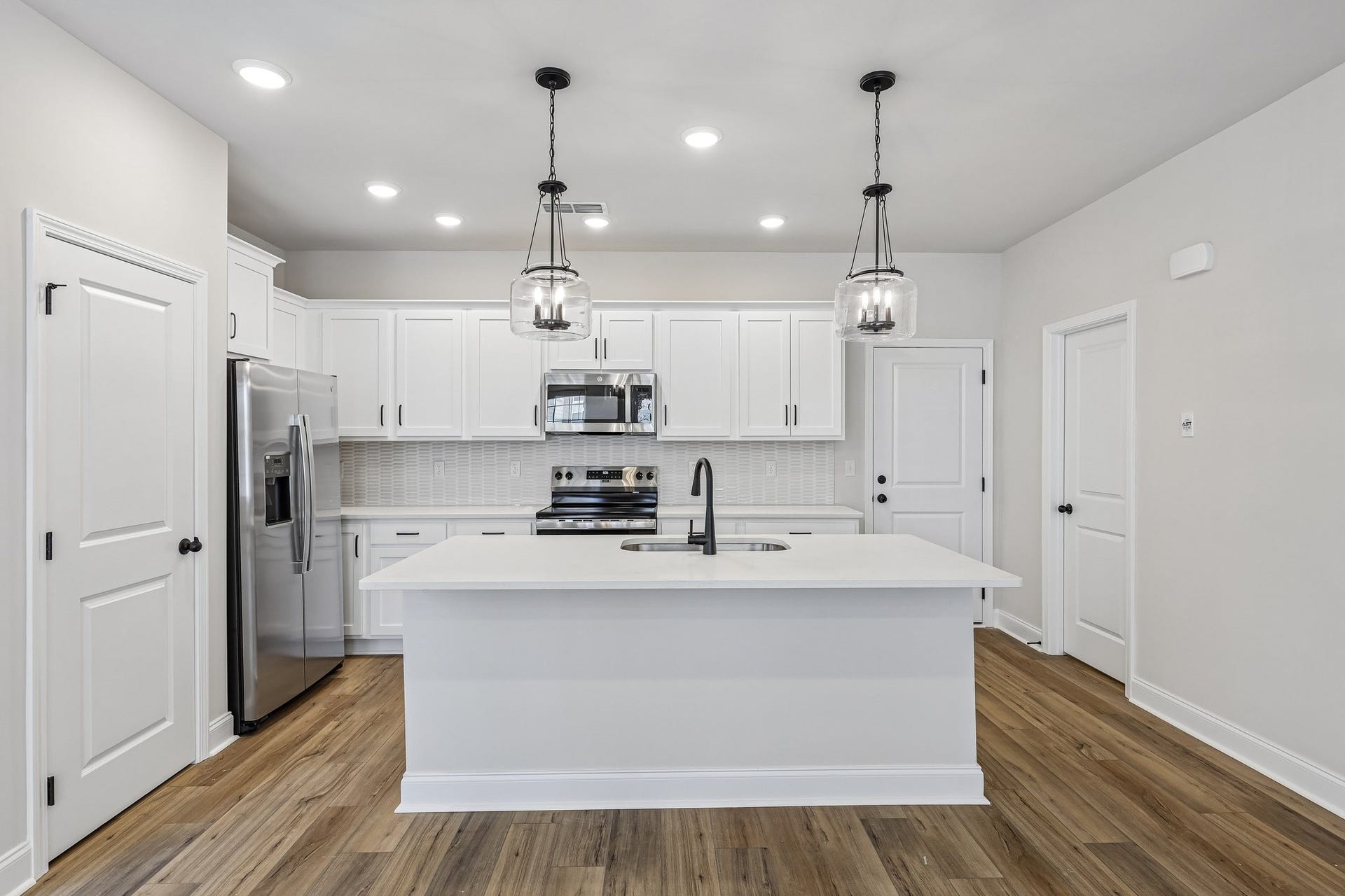 2718 Willowoak Trl, #2901, Murfreesboro, TN 37129 The kitchen features sleek white cabinetry with soft-close doors, quartz countertops, and a stylish mosaic tile backsplash. Black hardware, pendant lighting, and stainless-steel appliances perfectly accentuate the modern kitchen design.