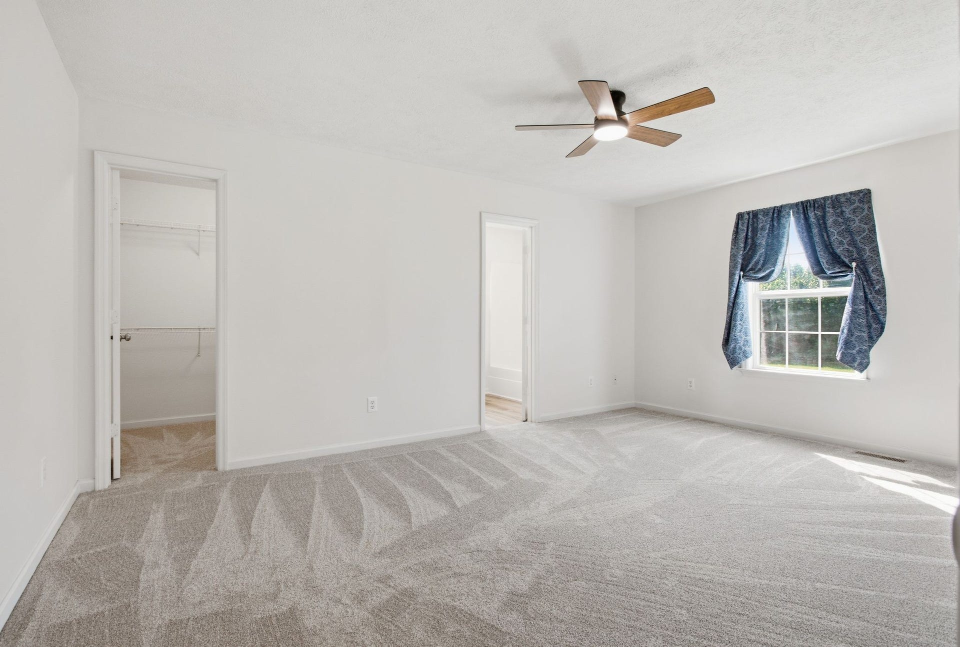 Primary suite located on the main floor with spacious walk-in closet, new carpet, new fan/light
