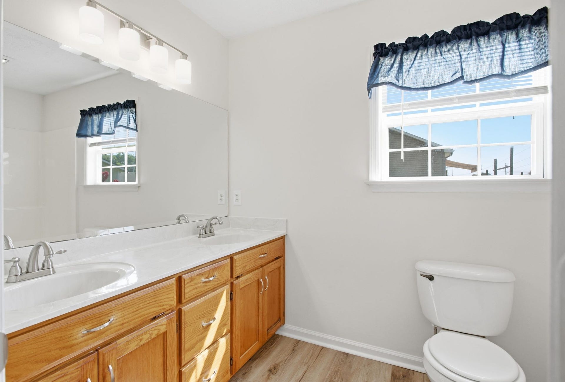 Primary Bathroom with new lighting, flooring, double sinks, faucets and commode seat.