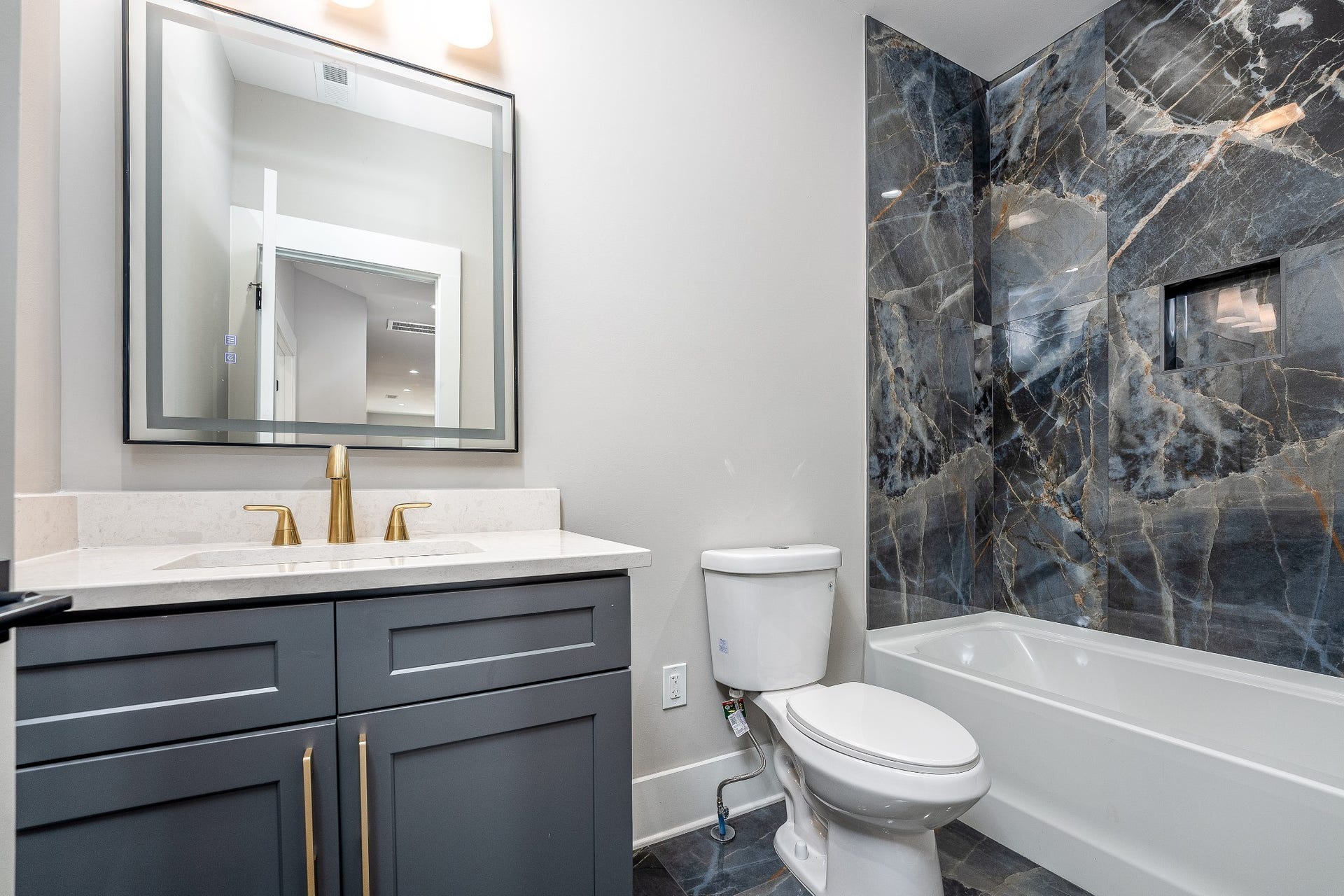 428 E Trinity Ln, #B, Nashville, TN 37207 Guest Bedroom Hallway access Bathroom with Shower/Tub combo, Italian tile and floor surround. Quartz Vanity with Lighted Mirror and additional accent lighting, custom cabinet with luxe brass handles.
