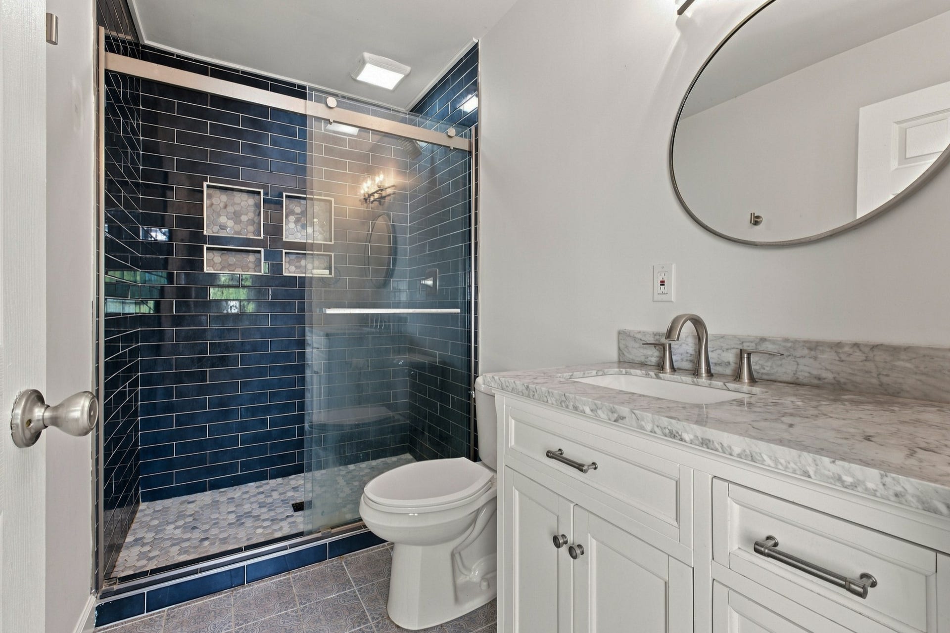 3312 Masonwood Dr, Nashville, TN 37207 The beautifully renovated primary bath showcases a custom-tiled walk-in shower with frameless glass, a marble-top vanity, and timeless designer finishes throughout.