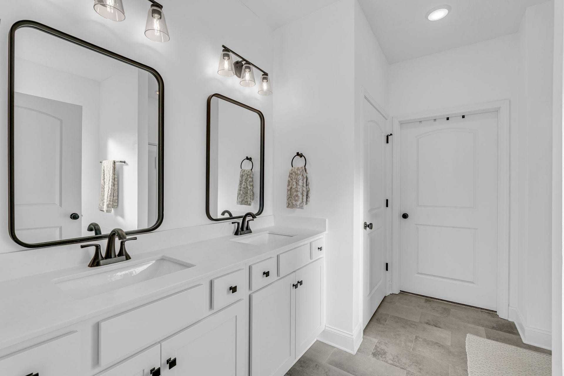 The primary bath is spacious with double sinks and black accents.