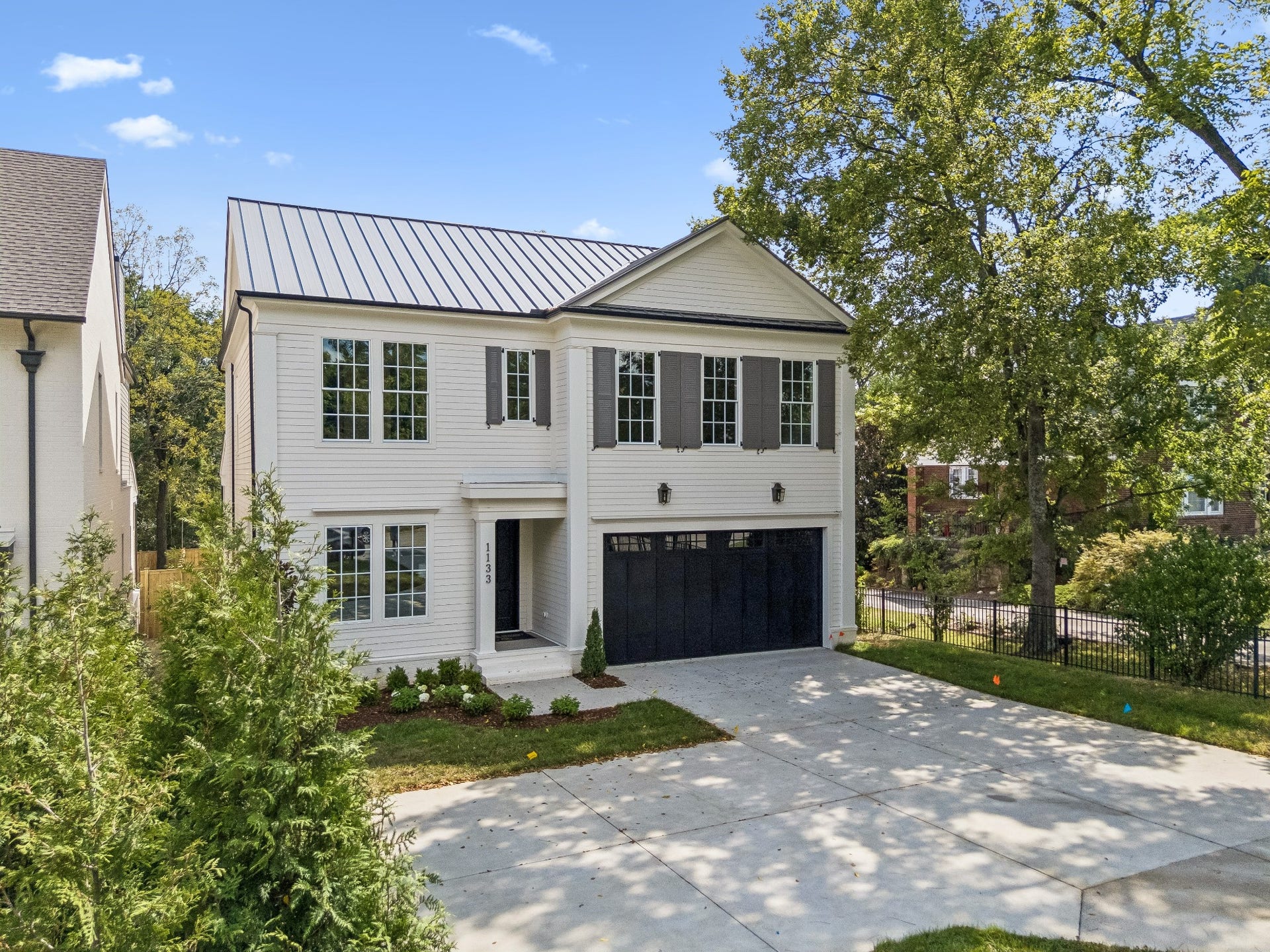 1133 Maplehurst Ln, Nashville, TN 37204 Timeless architecture and a classic exterior create an elegant first impression, complemented by a metal roof, mature trees, thoughtful landscaping, and an attached two-car garage.