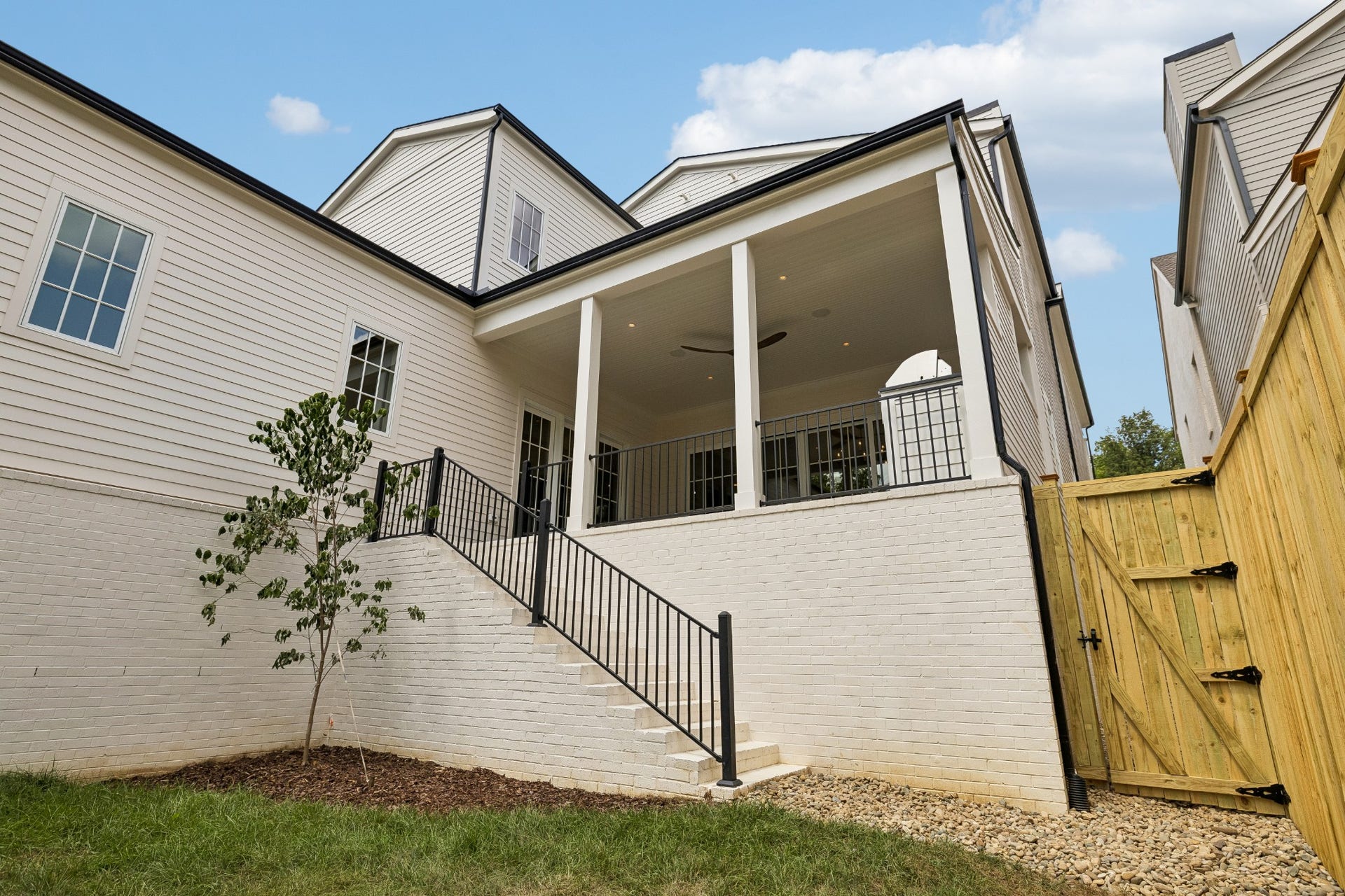 1133 Maplehurst Ln, Nashville, TN 37204 Wide exterior stairs connect the covered porch directly to the backyard, providing easy access between the homes outdoor entertaining area and lawn.