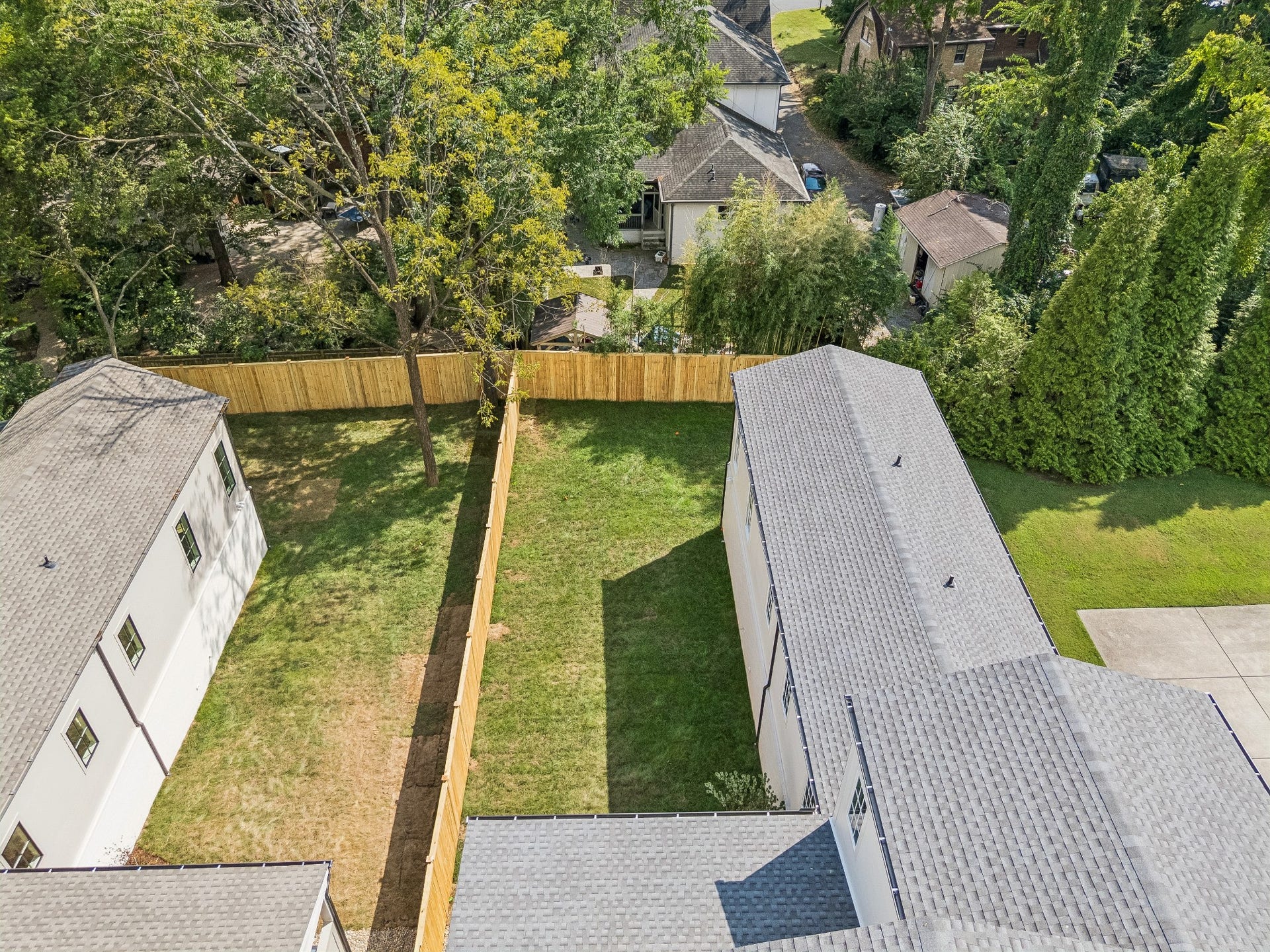 1133 Maplehurst Ln, Nashville, TN 37204 A wide view of the rear exterior highlights the homes substantial footprint, covered outdoor living space, walk-in crawlspace access, and large private backyard.