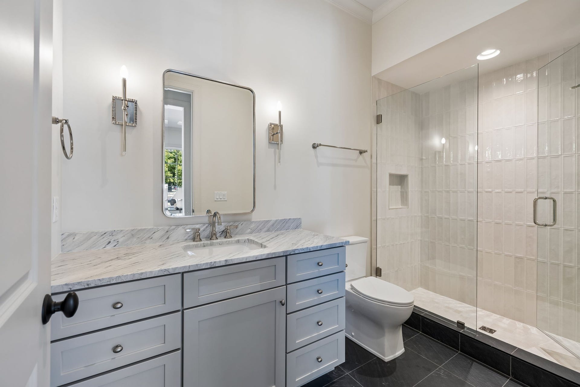 1133 Maplehurst Ln, Nashville, TN 37204 Beautiful full bath connects directly to the main-level spare bedroom, currently staged as an office, creating a flexible guest suite or private first-floor bedroom. Features include a marble-topped vanity and spacious glass-enclosed tiled shower.