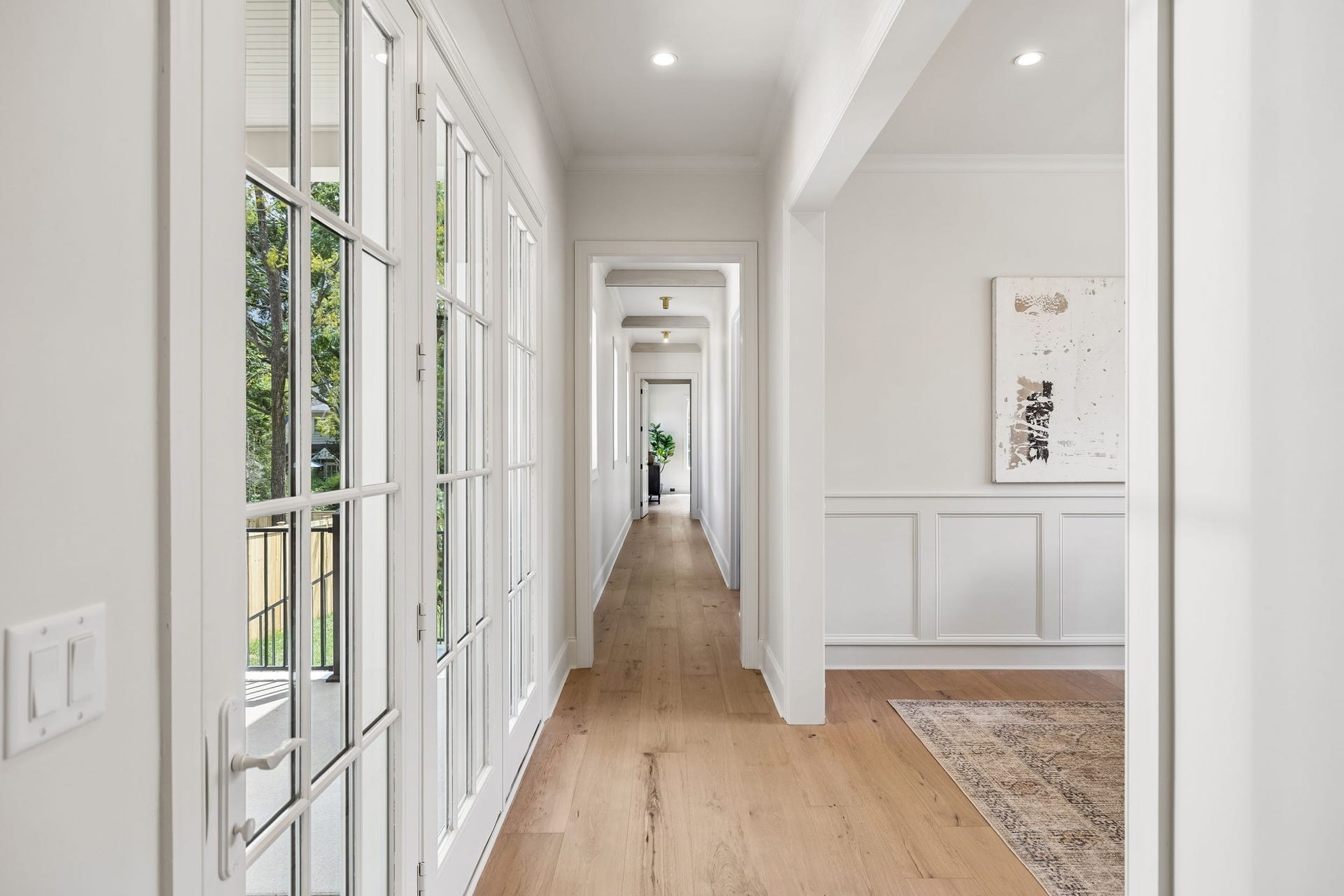 1133 Maplehurst Ln, Nashville, TN 37204 Light-filled hallway leads to the private primary wing, creating separation from the main living areas while maintaining an open, connected flow. Hardwood floors, architectural detailing, and walls of glass elevate the transition throughout the home