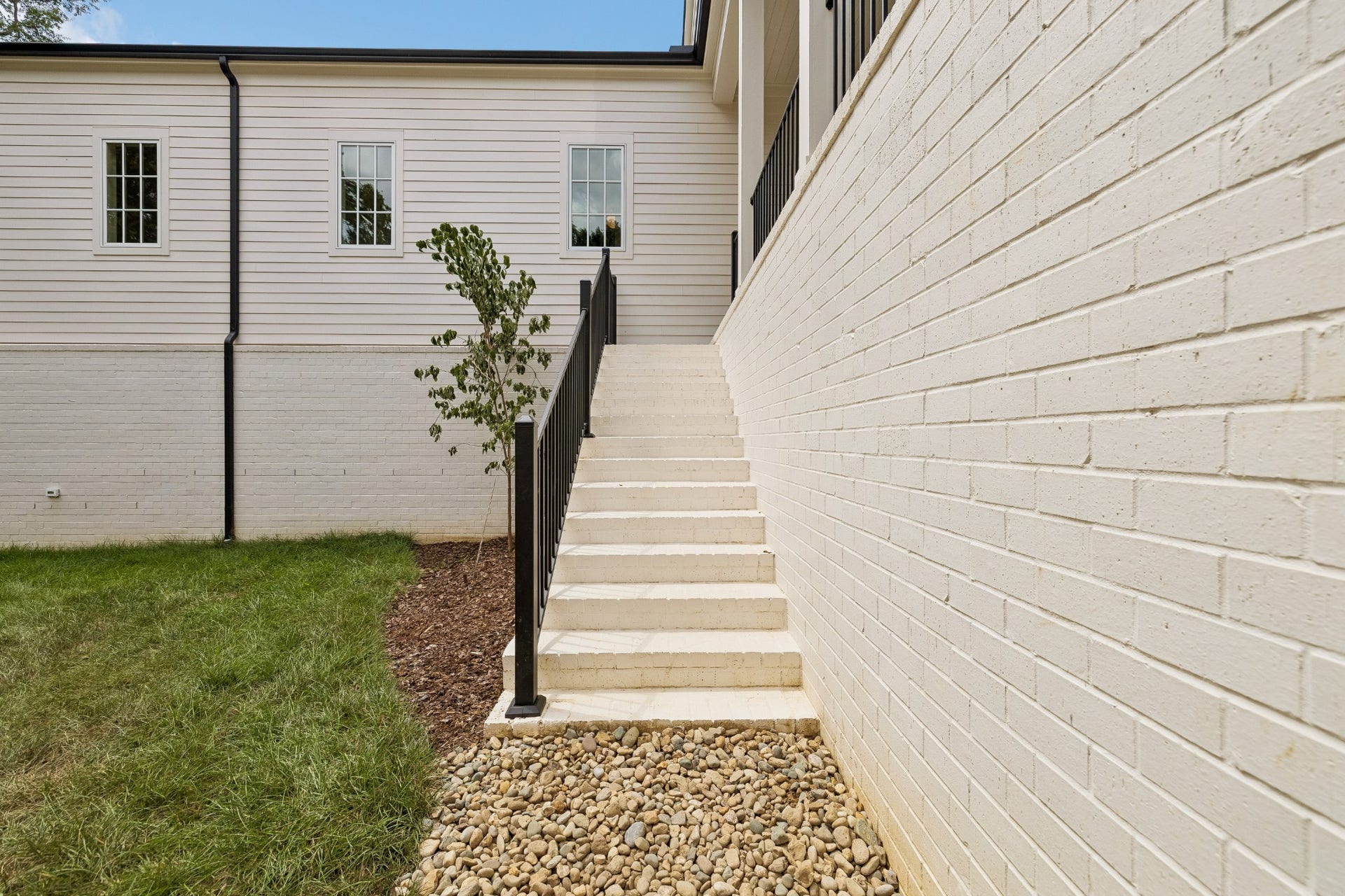 1133 Maplehurst Ln, Nashville, TN 37204 Wide exterior stairs connect the covered porch directly to the backyard, providing easy access between the homes outdoor entertaining area and lawn.