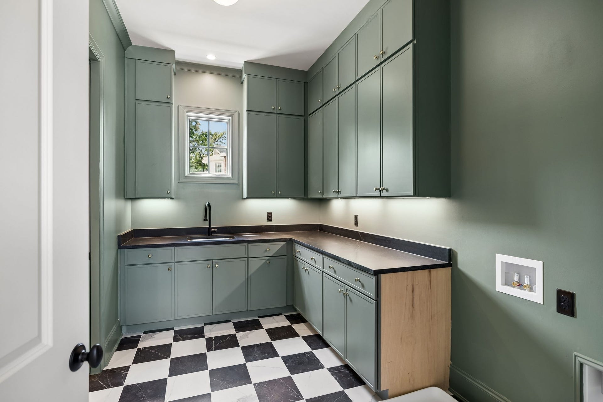 1133 Maplehurst Ln, Nashville, TN 37204 Stylish main-level laundry room features abundant cabinetry, utility sink, generous counter space, and a striking black-and-white checkerboard floor. Conveniently accessible directly from the primary closet or retreat hallway.