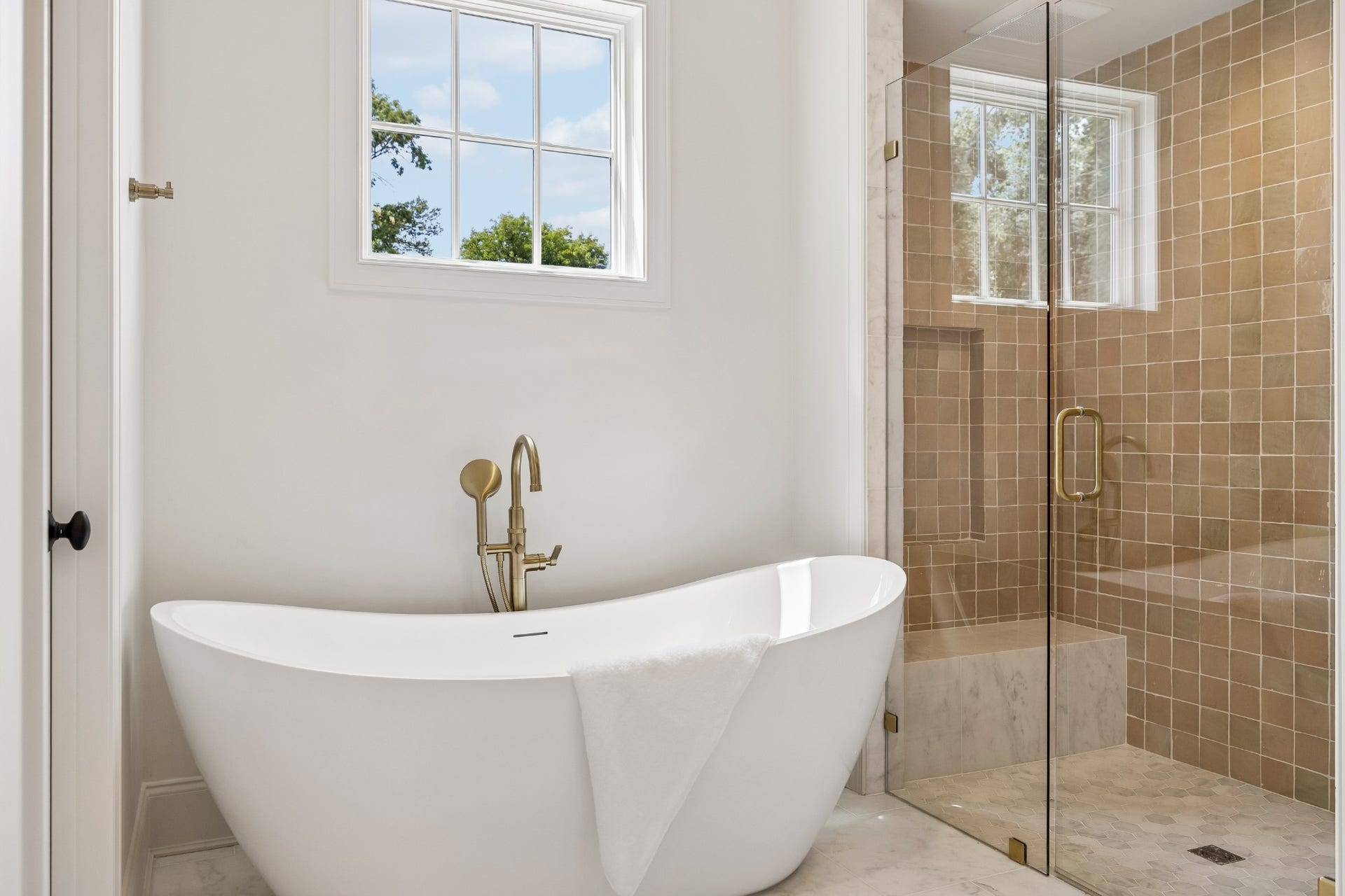 1133 Maplehurst Ln, Nashville, TN 37204 Spa-inspired primary bath features a freestanding soaking tub, oversized glass-enclosed shower, marble flooring, beautiful tilework, and elegant brass fixtures.