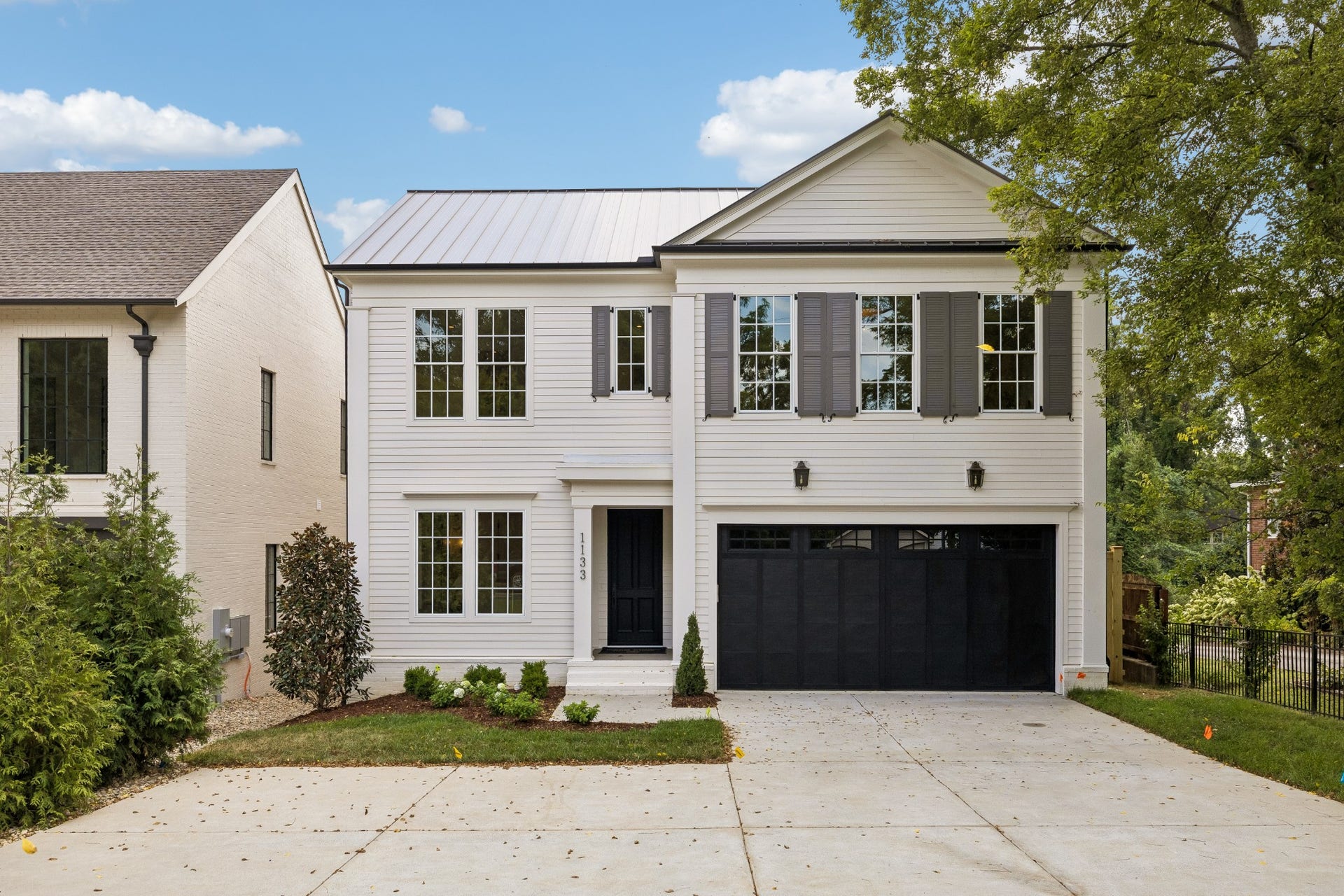 1133 Maplehurst Ln, Nashville, TN 37204 Timeless architecture and a classic exterior create an elegant first impression, complemented by a metal roof, mature trees, thoughtful landscaping, and an attached two-car garage.
